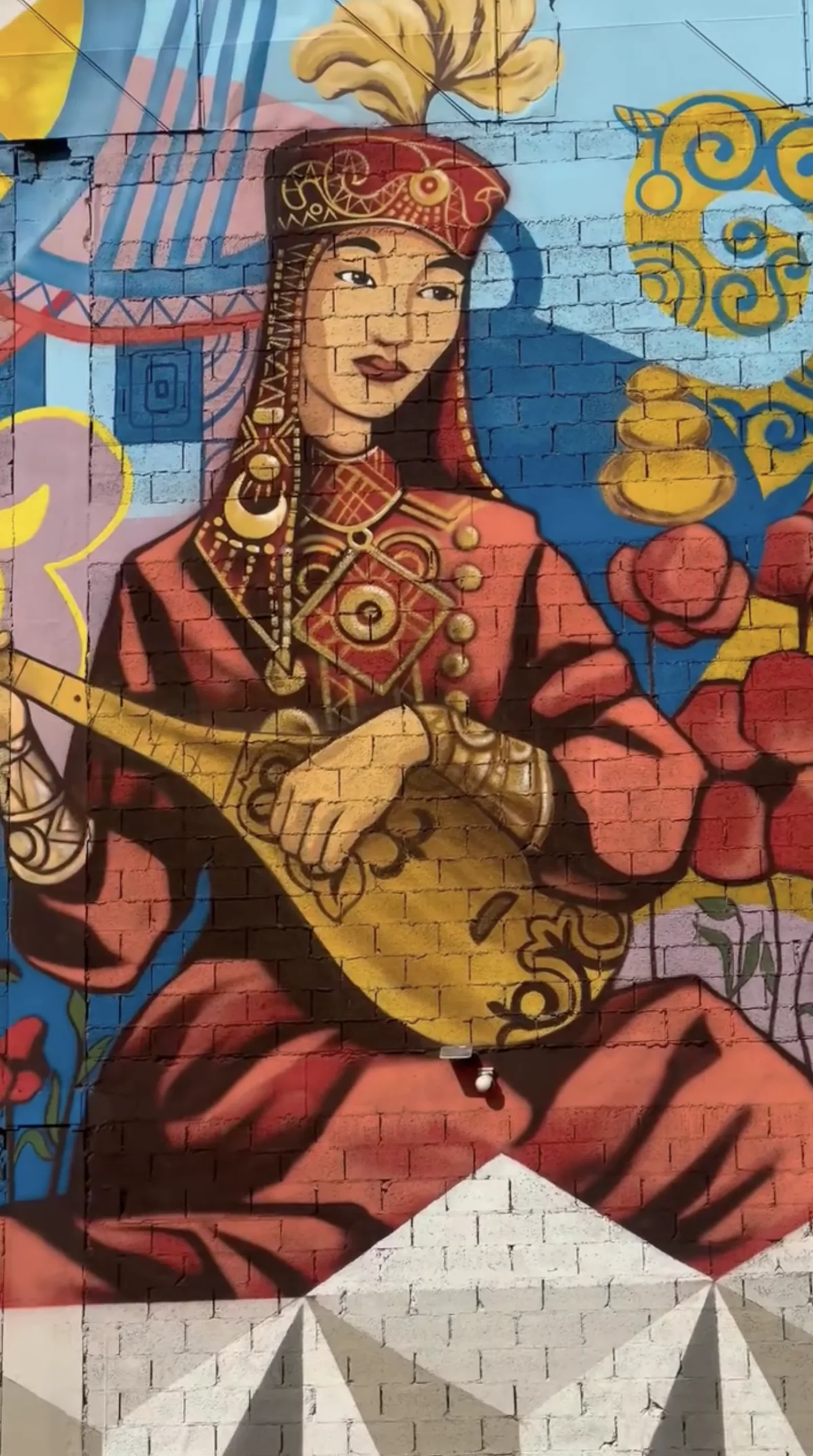Colorful mural of a woman playing the dombra